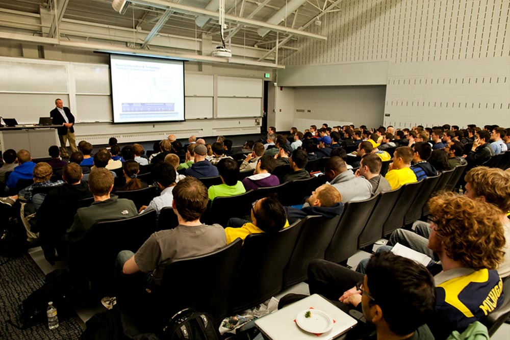 people facinga large screen in a lecture hall